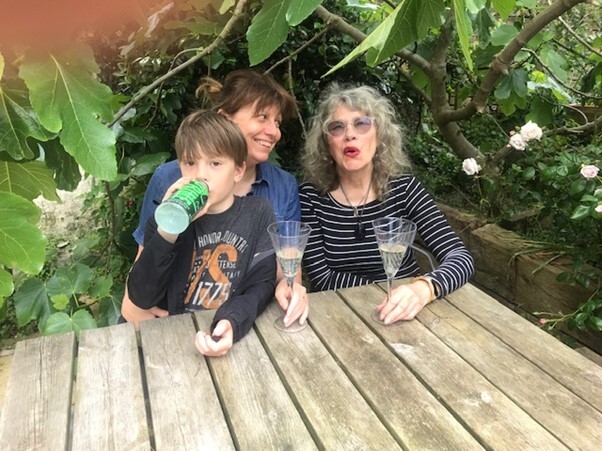 A young boy sits with two woman behind a wooden table