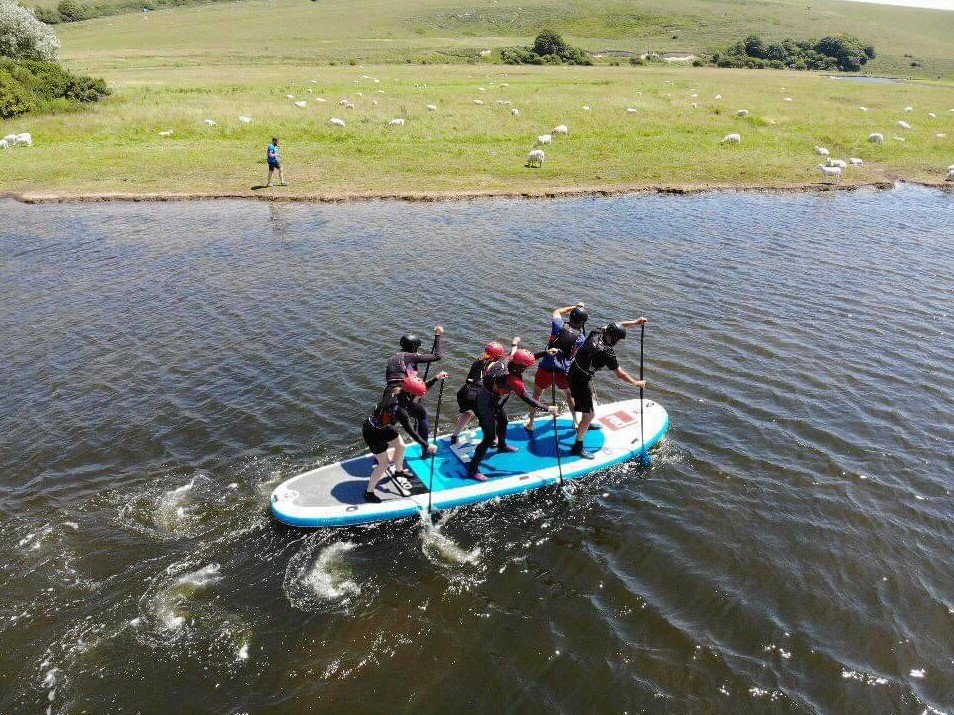 buzz active - six people paddle boarding down a river