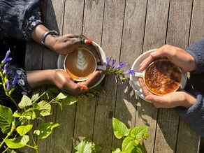 two people hold their hands around a cups of coffee