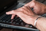 Hands typing laptop keyboard