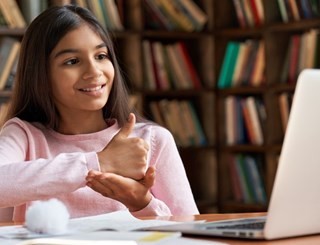 Young girl signing to a friend on a laptop