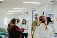 A group of adults stood around in a circle chatting.