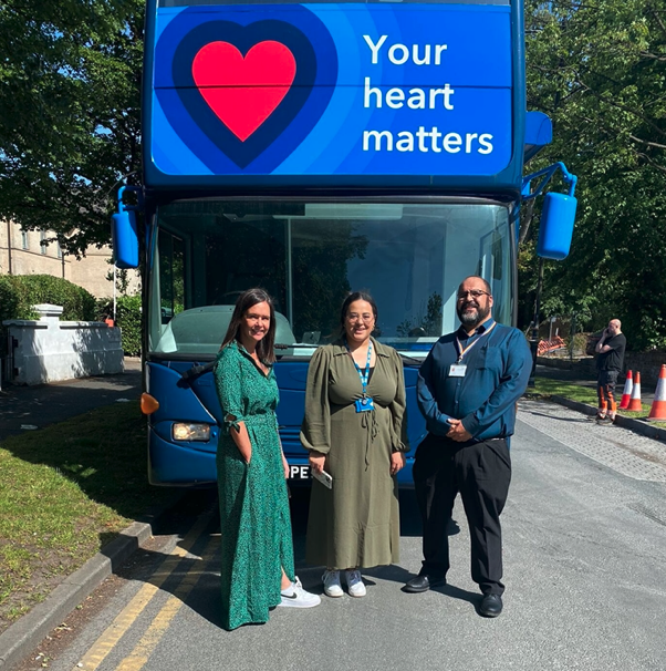 Three people stood in front of a blue bus with the words 'Your heart matters' on it. 