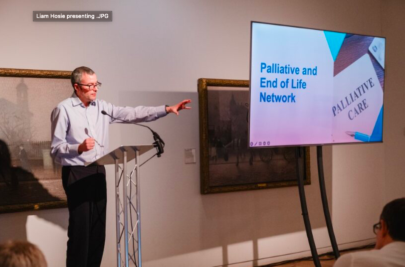 Man stood on stage, presenting to an audience