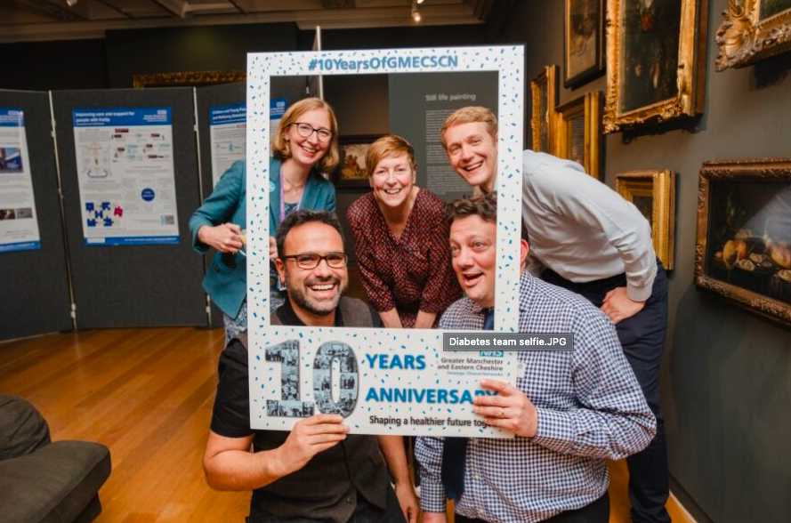 Five people having their photo taken inside a selfie frame