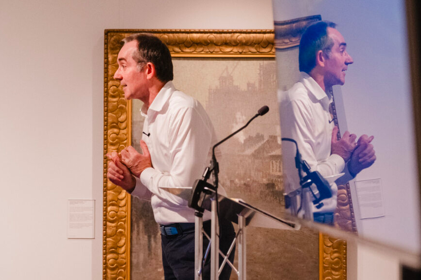 A photo of a person, with their image reflected on nearby glass