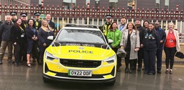 Image: Representatives from partner organisations involved in the pilot smile while stood next to police car
