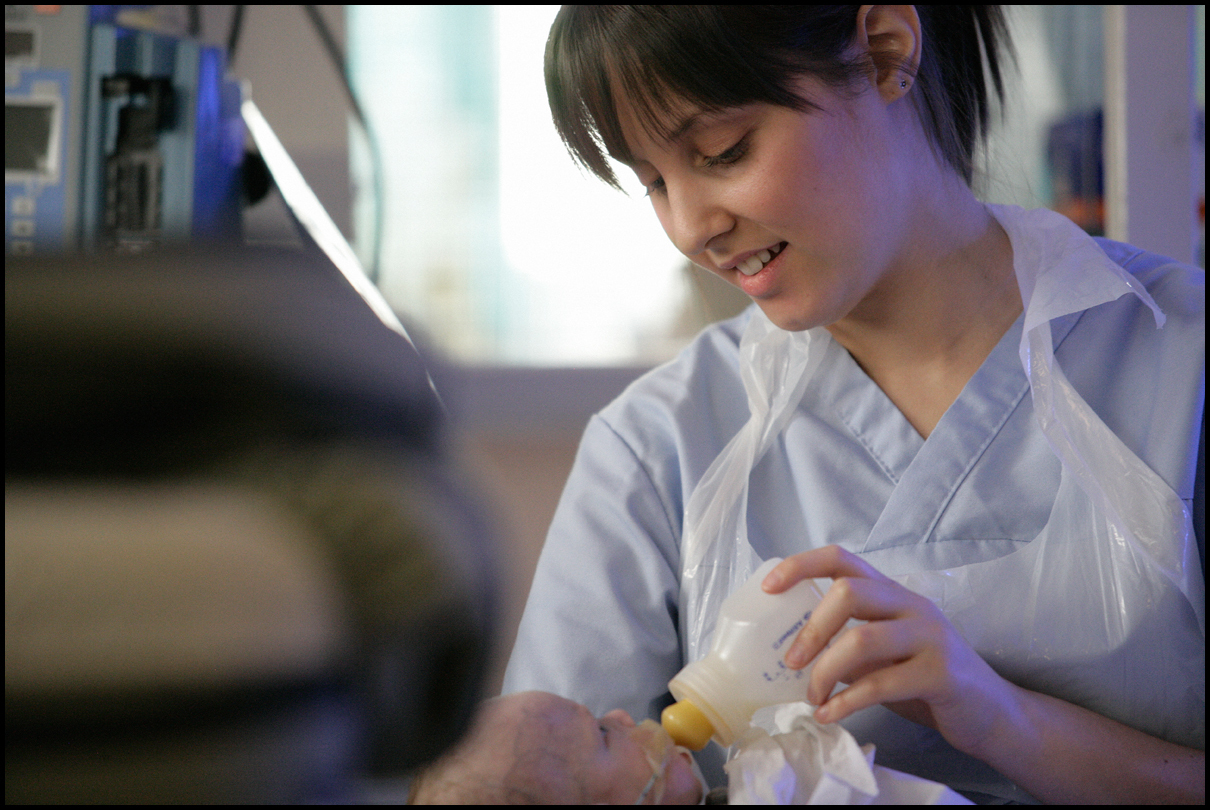 A neonatal nurse feeds a baby with a bottle