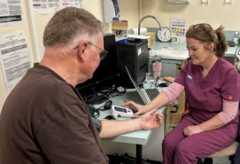 Health professional with patient, taking blood pressure reading.
