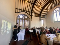 Groups of people wearing headphones, sat round tables in the Made by Mortals breakout