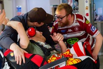 Photo of three people at Plattbridge community centre hugging, taken by Elephants Trail