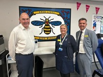 Three people stood together infront of the donation flag