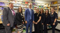 a group of people stood together smiling in front of a pharmacy shelf