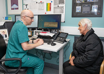 A GP talking to an elderly patient sat at a desk in GP surgery