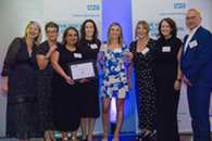group shot of colleagues on stage holding the award