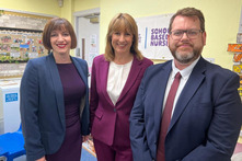 three people stood together in a primary school classroom