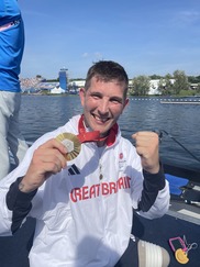 head and shoulders shot of a male in a boat smiling holding a medal
