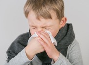 child sneezing into a tissue