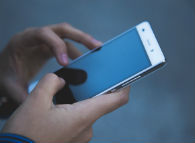 Smartphone user holds phone in hand, screen showing image of a bedroom.