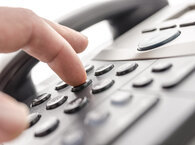 A hand pressing keys on a telephone keypad.