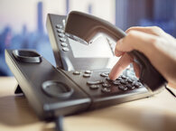 A hand dialling a telephone keypad