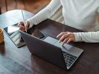 Woman using a digital pencil with a tablet while touching the pad of a laptop.