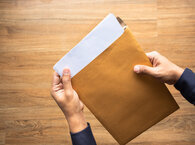 Two hands holding an envelope with a document inside