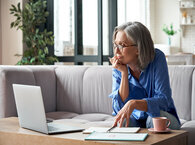 Woman sitting on a sofa making an application on laptop with notebooks open