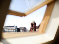 An open skylight with a view of an urban skyline.