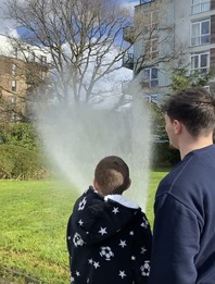 A fire fighter and a child using a hose