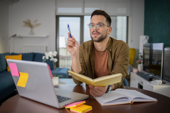 a man sat at his computer taking notes