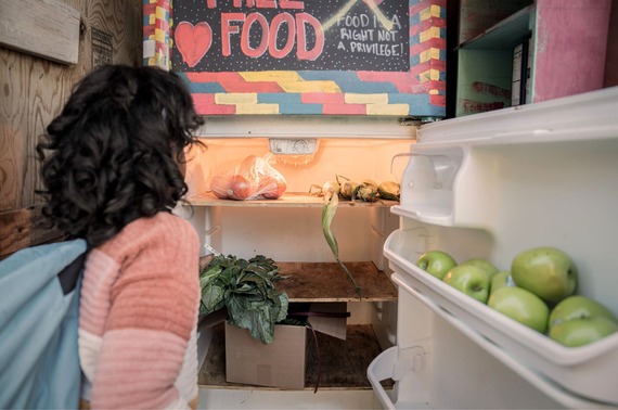 a girl looking into a community fridge