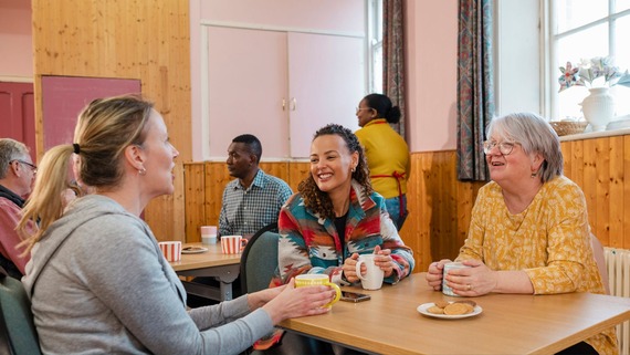 three women sat talking to each other at a community hub