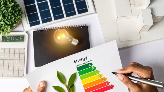 a table top filled with energy saving imagery including a light bulb, solar panel, pen, energy efficiency chart and a calculator.