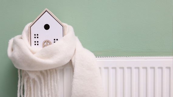 A small model house, wrapped in a scarf, on top of a radiator