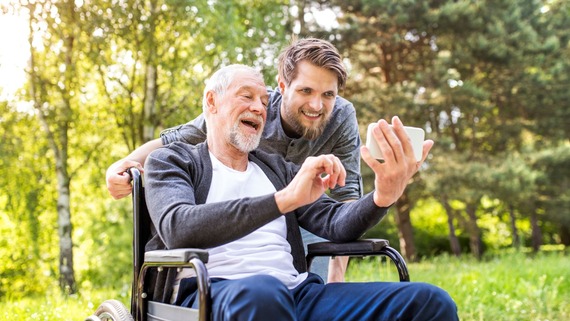 a carer pushing an elderly man in a wheelchair