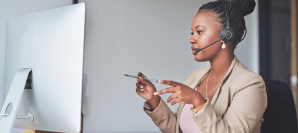 Woman sitting at a computer wearing a headset and talking