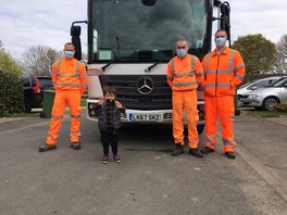 Theo stands at the front of the bin truck with three crew members and gives the camera a thumbs up