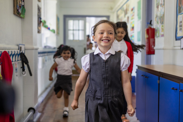 three Primary School Children running down a corridor