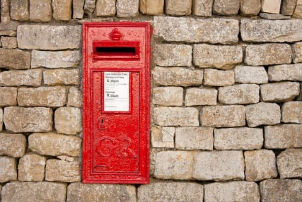 a red postbox situated in a brick wall