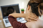 Female homeworker holding neck in pain