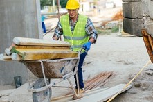 construction worker moving materials across site in a wheelbarrow