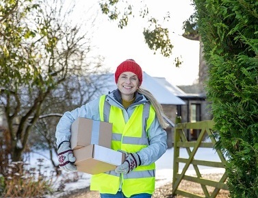 Female delivery worker holding parcels in the snow