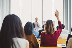 Woman raising hand to ask trainer a question in a training room