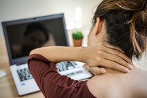 female worker at desk, feeling a neck strain