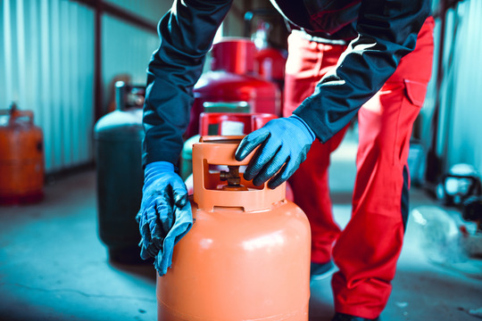 Worker Cleaning Gas Cylinder In Storage 