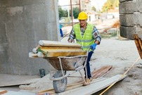 construction worker wheelbarrowing material on site