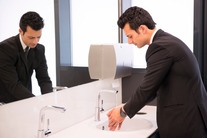 Male washing hands in workplace toilet