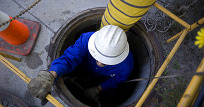 worker lowering into manhole