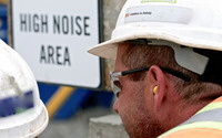 site worker next to a noise warning sign